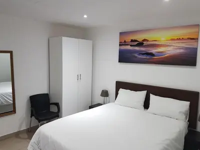 a bedroom with a white bed and a painting on the wall at Relaxing guest House in the heart of Ndabeni in Cape Town