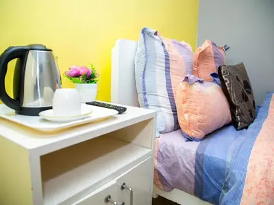 a bed with a table with a coffee maker and pillows at Relaxing guest House in the heart of Ndabeni in Cape Town