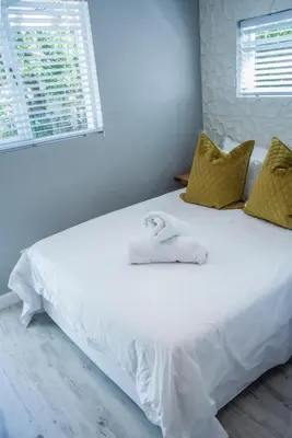 a white bed with a towel on top of it at Seven on Flora- Hot Tub, Modern with amazing outside area in Hermanus