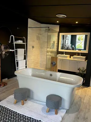 a white bath tub with two stools in a bathroom at Modern Spacious Cottage with Hot Tub, Flora Studio in Hermanus