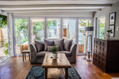 a living room with a couch and a table at Modern Spacious Cottage with Hot Tub, Flora Studio in Hermanus