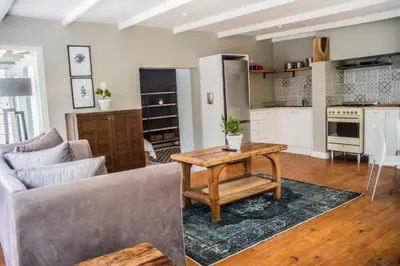 a living room with a couch and a table at Modern Spacious Cottage with Hot Tub, Flora Studio in Hermanus