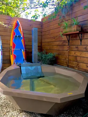 a bath tub with a surfboard sitting in it at Modern Spacious Cottage with Hot Tub, Flora Studio in Hermanus
