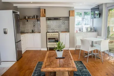 a kitchen with white cabinets and a table with a potted plant at Modern Spacious Cottage with Hot Tub, Flora Studio in Hermanus