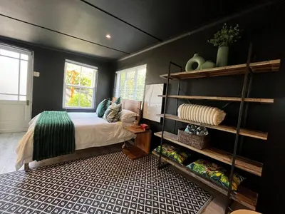 a bedroom with a bed and a window and shelves at Modern Spacious Cottage with Hot Tub, Flora Studio in Hermanus