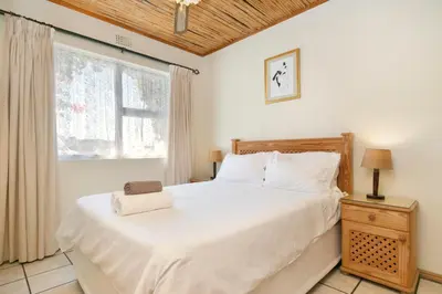 a bedroom with a large white bed and a window at The Bohemian Guesthouse in Cape Town