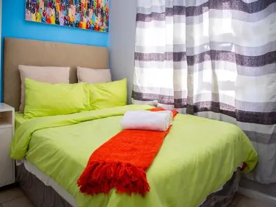 a bedroom with a green bed with a red blanket at Relaxing guest House in The heart of Ndabeni in Cape Town
