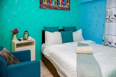 a blue bedroom with a bed and a chair at Relaxing Guest House in the heart of Ndabeni in Cape Town