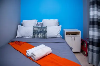 a bed with two towels on top of it at Relaxing Guest House in the heart of Ndabeni in Cape Town