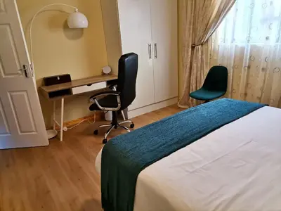 a bedroom with a bed and a desk and a chair at Shalom Self catering in Cape Town