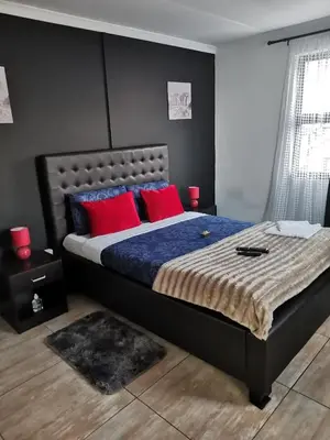 a bedroom with a large bed with red pillows at ILITHA PARK in Cape Town