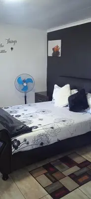 a bedroom with a bed with a black and white comforter at ILITHA PARK in Cape Town