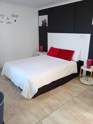 a bedroom with a large white bed with red pillows at ILITHA PARK in Cape Town