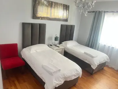 two beds in a bedroom with a chair and a chandelier at izuba Lodge in Cape Town