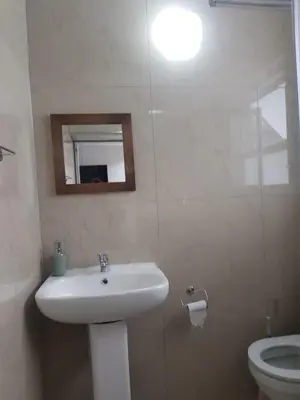 a white bathroom with a sink and a toilet at izuba Lodge in Cape Town