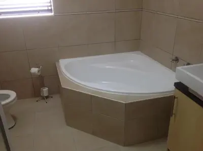 a bathroom with a bath tub and a toilet at Sikelela Guest House in Cape Town