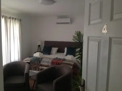 a bedroom with a bed with two chairs and a table at Sikelela Guest House in Cape Town