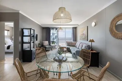 a living room with a glass table and chairs at Horizon Bay 301 by CTHA in Bloubergstrand