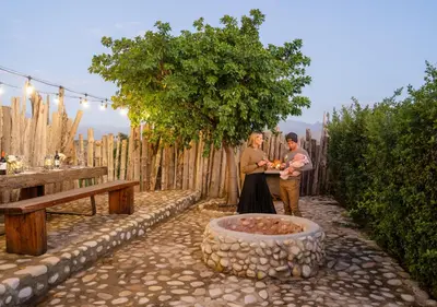 a man and a woman standing next to a fire pit at Ludus Magnus Boutique Hotel in Franschhoek