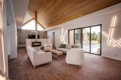 a living room with white furniture and a wooden ceiling at Ludus Magnus Boutique Hotel in Franschhoek