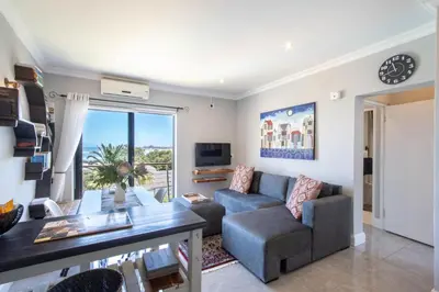 a living room with a couch and a table at Apartment18Lifestyle Gordons Bay Beachfront in Gordonʼs Bay