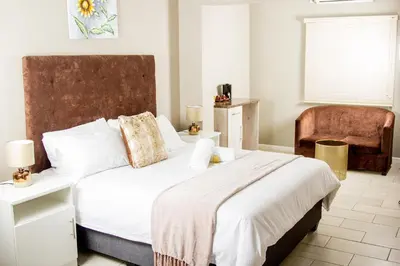 a bedroom with a large bed and a chair at 103onWallace Self Catering Guest House in Cape Town