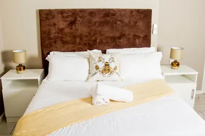 a white bed with two towels and two lamps at 103onWallace Self Catering Guest House in Cape Town