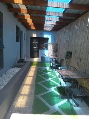 a patio with tables and chairs and a green floor at Victoria Guest Lodge in Bellville