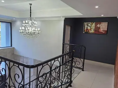 a dining room with a chandelier and a staircase at Victoria Guest Lodge in Bellville