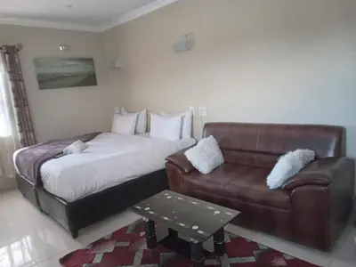 a bedroom with a bed and a couch at Victoria Guest Lodge in Bellville