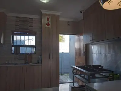a kitchen with wooden cabinets and a sink and a stove at Victoria Guest Lodge in Bellville
