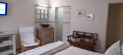 a bedroom with a shower and a bed and a chair at Barlinka lane Selfcatering flatlet , Somerset West in Cape Town