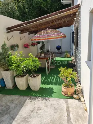 a patio with a table and an umbrella and potted plants at Barlinka lane Selfcatering flatlet , Somerset West in Cape Town