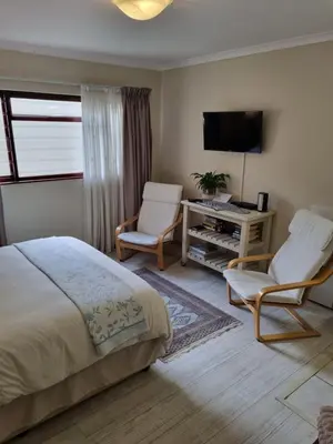 a bedroom with a bed and two chairs and a desk at Barlinka lane Selfcatering flatlet , Somerset West in Cape Town