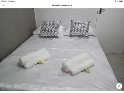 a white bed with two rolled towels on it at Tia Maria House in Cape Town