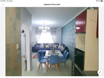 a living room with a table and blue chairs at Tia Maria House in Cape Town