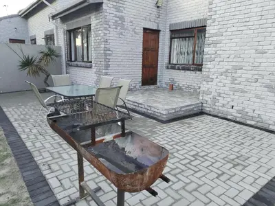 a patio with a table and chairs and a building at Tia Maria House in Cape Town