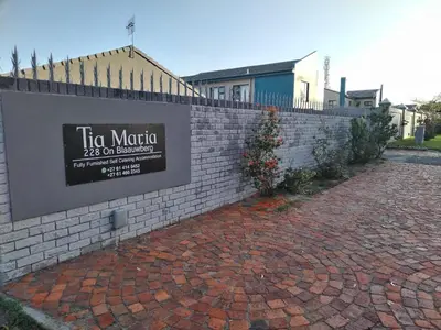 a sign on a brick wall next to a brick sidewalk at Tia Maria House in Cape Town