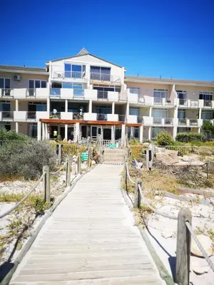 a boardwalk leading to a building on the beach at Cape Town Family Beachfront Apartment Leisure Bay in Cape Town
