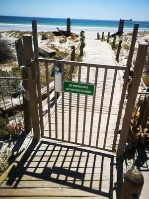a gate leading to a boardwalk to the beach at Cape Town Family Beachfront Apartment Leisure Bay in Cape Town