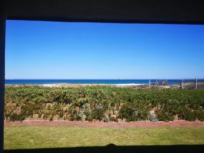 a view of the ocean from a window of a beach at Cape Town Family Beachfront Apartment Leisure Bay in Cape Town