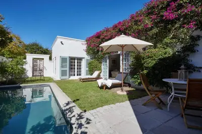 a backyard with a swimming pool and an umbrella at Tockie's Cottage in Franschhoek