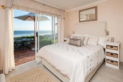 a bedroom with a bed and a view of the ocean at Hermanus Haven, entire home, on the sea, private pool, secure in Hermanus