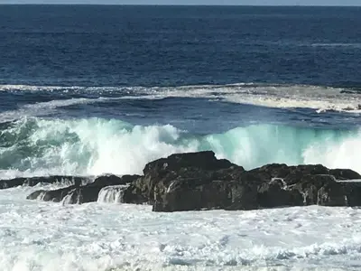 a wave breaking on a beach with rocks at Hermanus Haven, entire home, on the sea, private pool, secure in Hermanus