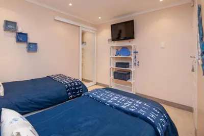 a bedroom with a bed and a flat screen tv at Hermanus Haven, entire home, on the sea, private pool, secure in Hermanus