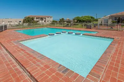 a large swimming pool with blue water on a brick patio at Hermanus Haven, entire home, on the sea, private pool, secure in Hermanus