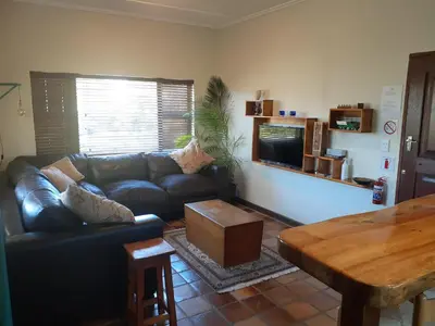 a living room with a leather couch and a table at Upstairs in Cape Town