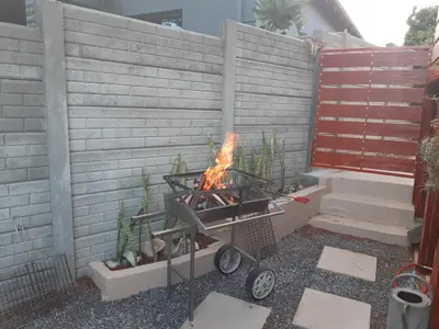 a fire pit in a backyard with a brick wall at Upstairs in Cape Town
