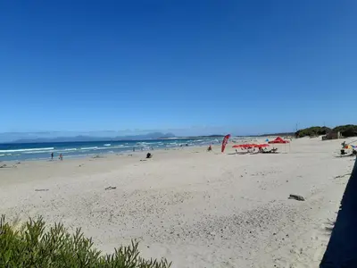 a beach with people on the sand and the ocean at Upstairs in Cape Town