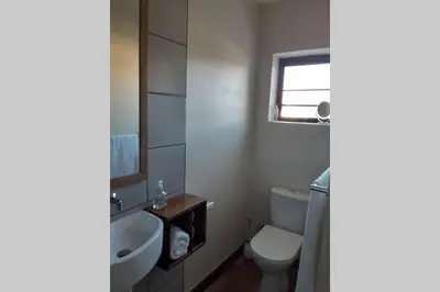 a bathroom with a sink and a toilet and a window at Upstairs in Cape Town